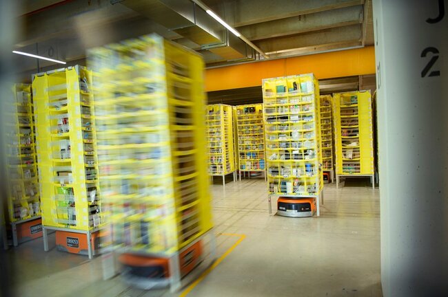 輸送ロボットがアマゾン物流センターの製品倉庫で輸送可能な棚を移動させている　