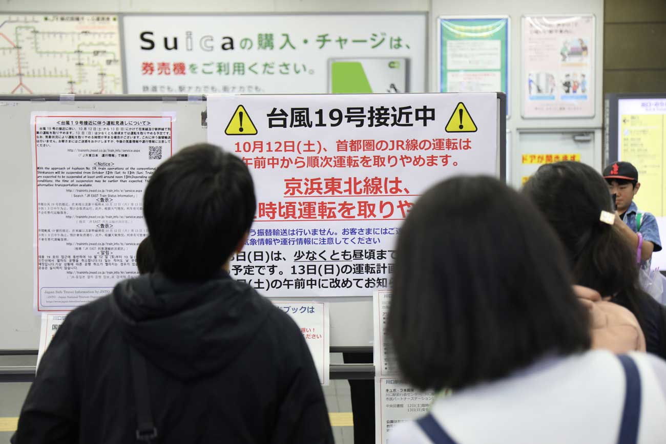 計画運休の貼り紙を見る乗客たち