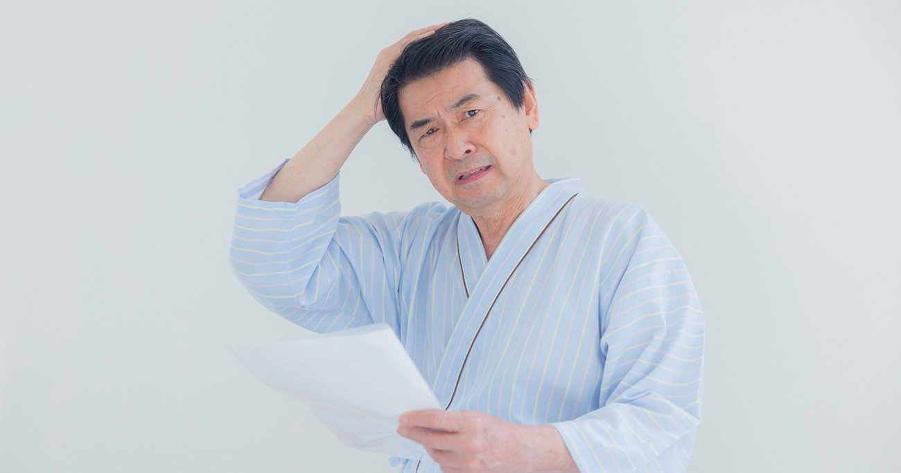 書類を見ながら頭を抱える男性